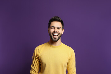 Obraz premium Young man laughing on purple background. Funny joke