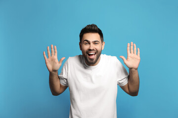 Naklejka premium Young man laughing on light blue background. Funny joke