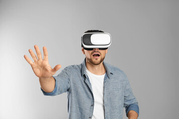 Man using virtual reality headset on grey background