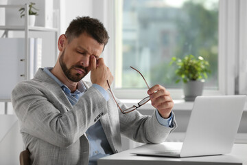 Man suffering from eyestrain at desk in office