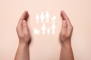Man holding hands around cutout paper silhouette of family on pink background, top view. Insurance...