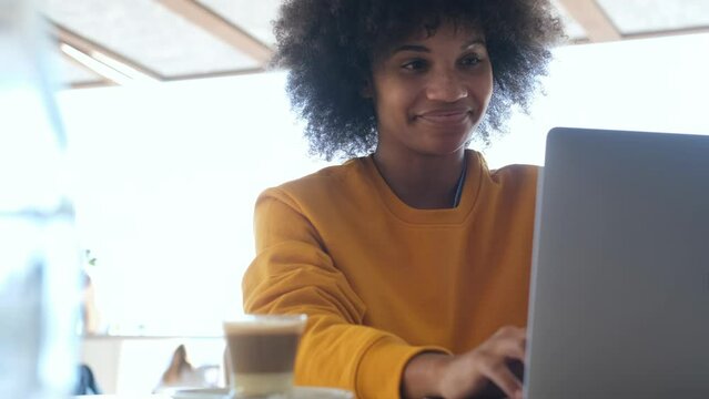 beautiful African or American businesswoman working with laptop or computer in the street of the city wearing medical mask to prevent covid-19