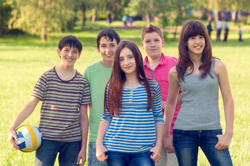 Fototapeta na wymiar Teenagers boys and girls standing on the meadow grass on a sunny summer day