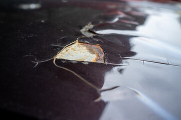 Broken part of car body with rusty and putty is too thick. Cracked and peeling paint on an old car.
