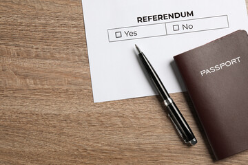 Referendum ballot with pen and passport on wooden table, flat lay. Space for text