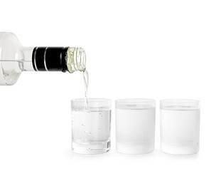 Pouring vodka from bottle in glass on white background