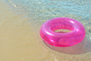 Bright inflatable ring on sandy beach near sea. Space for text