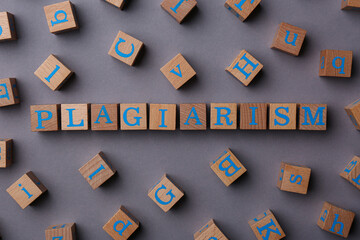 Wooden cubes with word Plagiarism on grey background, flat lay