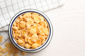 Bowl of tasty corn flakes on white wooden table, flat lay. Space for text