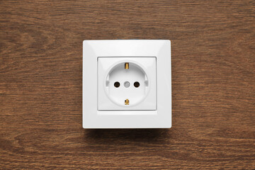 Modern plastic power socket on wooden table, top view