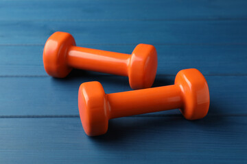 Orange vinyl dumbbells on blue wooden table