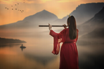 Woman in red Chinese ancient costume standing, playing a musical instrument on mountain background. 