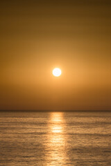Fototapeta na wymiar golden shining sun over sea with background of golden sky