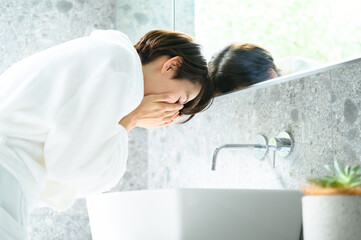 洗面所で顔を洗う女性