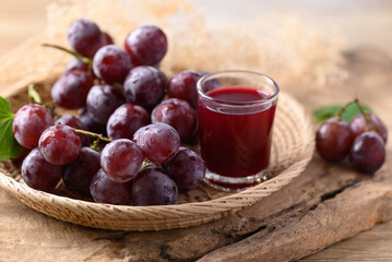 Red grape and juice in glass on wooden background, healthy drink