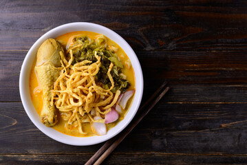 Northern Thai food (Khao Soi), Spicy curry noodles soup with chicken on wooden background, Local Thai food