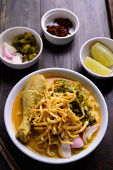 Northern Thai food (Khao Soi), Spicy curry noodles soup with chicken on wooden background, Local Thai food
