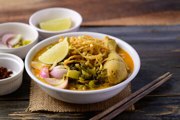 Northern Thai food (Khao Soi), Spicy curry noodles soup with chicken on wooden background, Local Thai food
