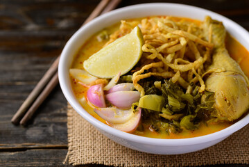Northern Thai food (Khao Soi), Spicy curry noodles soup with chicken on wooden background, Local Thai food