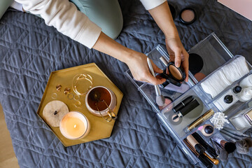 Woman hands tidying up putting powder container into acrylic storage box makeup products placement