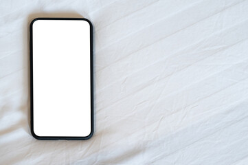 Close up smartphone with an empty white screen on the fabric texture bed in the bedroom.