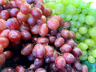 Huge bunches of grapes lie on the counter of a large store in Granville Island Red and green grapes are very appetizing and healthy Natural product for delicious food