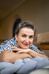 Obraz premium Portrait smiling middle aged gray haired woman posing with hands near chin lying on gray plaid floor
