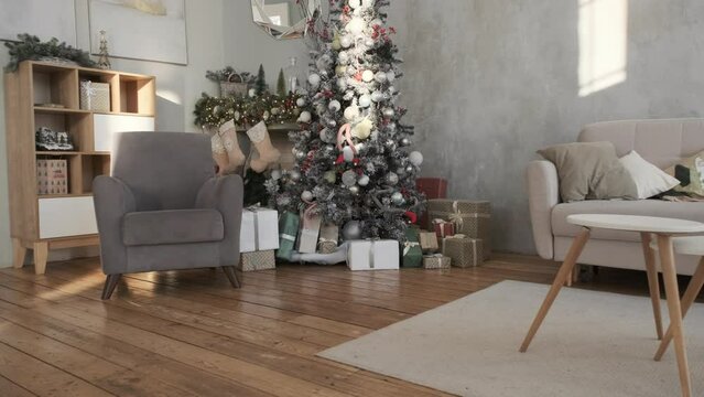 Beautiful festive interior of living room with Christmas tree, gifts, garlands and stockings on a fireplace. Winter holidays at home