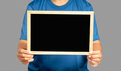 Close-up of hands holding a blank mini blackboard while standing on a gray background