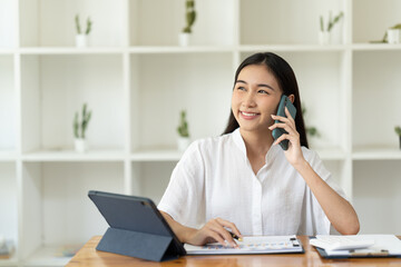 Asian businesswoman in formal suit in office happy and cheerful during using smartphone and working.