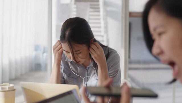 Young adult asia Gen Z female rolling eyes frown face to noisy rude shame worker in hybrid office toxic people loud noise. Moody bored woman stress work social issue angry upset annoy in boring job.