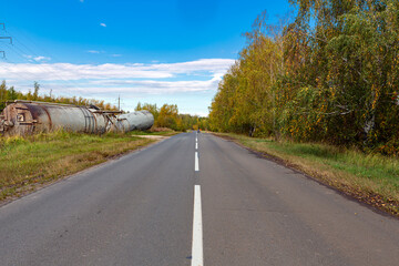 Autumn forest road goes into the blue sky.