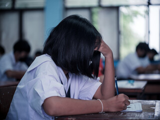 Students reading exam answer sheets exercises in classroom of school with headache and stress