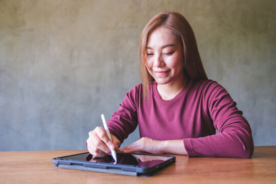 Portrait of a woman using stylus pen technology for working and writing on digital tablet screen