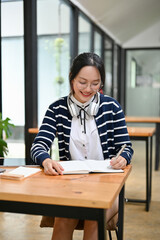 Beautiful young Asian female college student doing homework