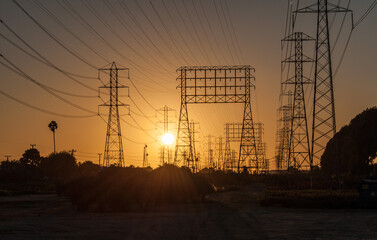 A maze of electrical transmission wires and towers in front of a golden sunset