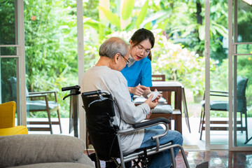Asian young woman nurse pills with help prescribes medicine to older disabled patient on wheelchair when elderly senior man patient's time to go home at nursing home care. Medicine and health care