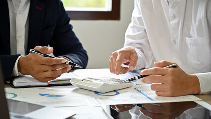 Two Asian businessmen analyzing sales and expenses data on the report. cropped shot