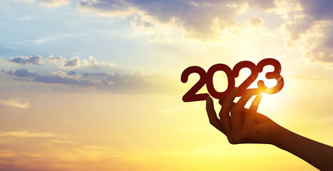 Silhouette hand holding 2023 year on sunset sky. Happy new year to plan and starting new life...