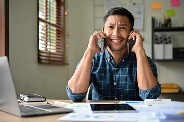 Confused and busy Asian businessman receives multiple phone calls at the same time