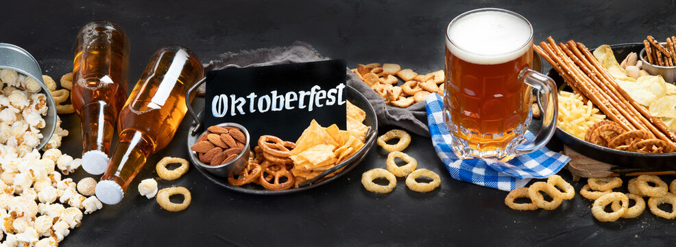 Assortment of beer and salty snacks on dark background.
