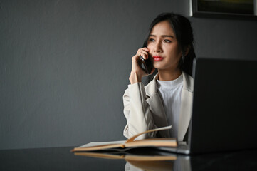 Stressed millennial Asian businesswoman having a serious phone call while working in the office.