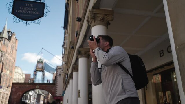 Young male photographer taking pictures in Chester city centre in slow motion with rotation around him.