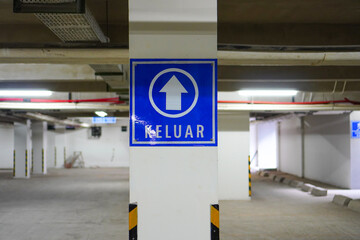 Exit sign symbol on basement. Underground parking garage. Exit sign on the driveway in parking garage. Keluar