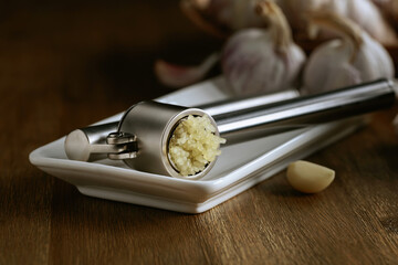 Garlic bulbs and garlic press on a wooden table.