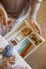 Female hands putting scissors into drawer with sewing accessories neatly placing organizing top view