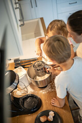 Caring mother cooking with daughter and son together family preparing waffles mixing dough