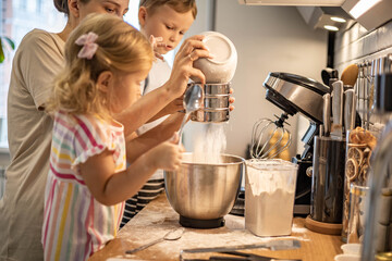Caring mother cooking with daughter and son together family preparing waffles mixing dough