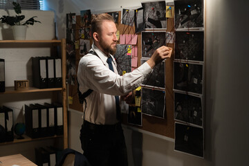 Detective looking at evidence board in office, clue and blueprints on mud board of investigator,...