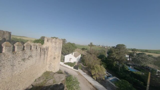 FPV aerial flies over castle wall and along medieval rampart wall walk